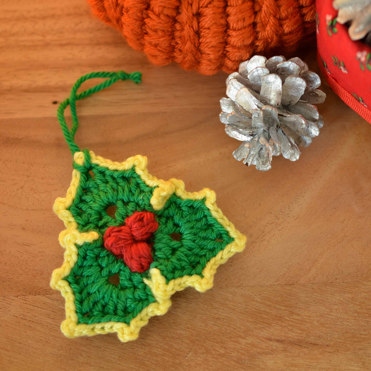 A holly leaf hanging ornament laying on the table.