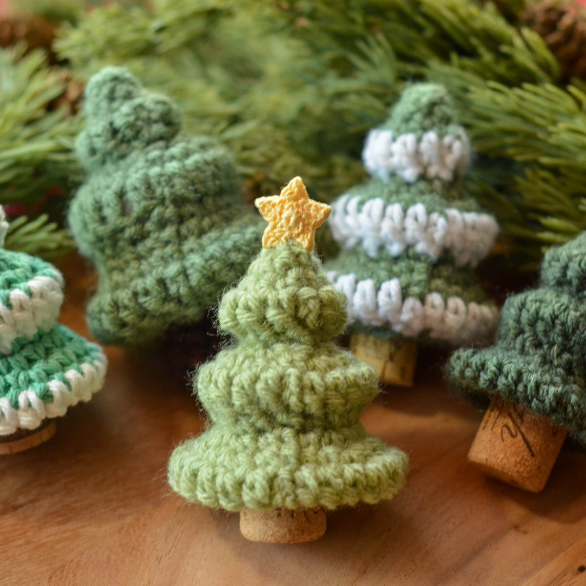 Several crocheted mini Christmas Tree standing on the table. One of them has a star on the top.