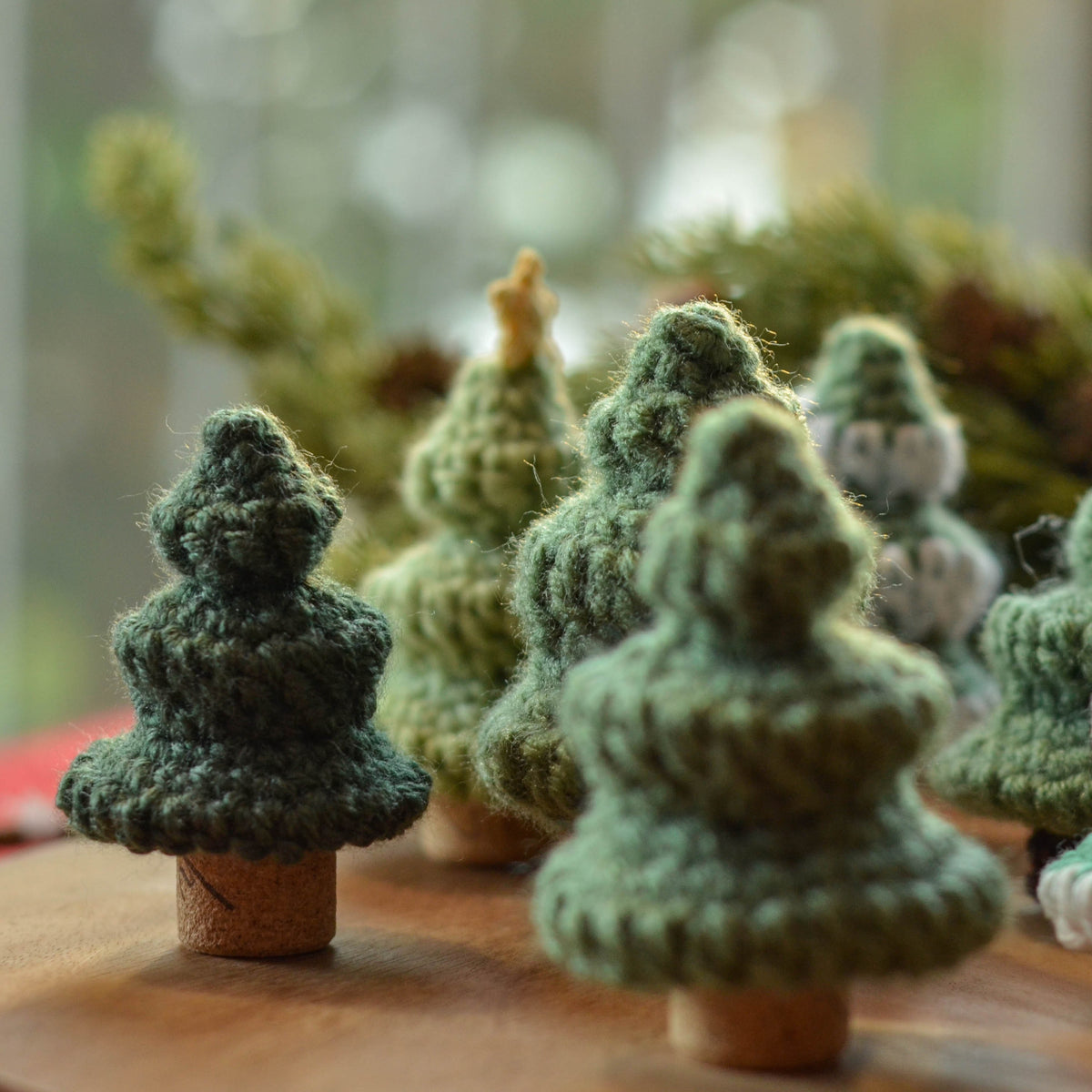 Several crocheted pine trees, using wine corks as tree trunks.