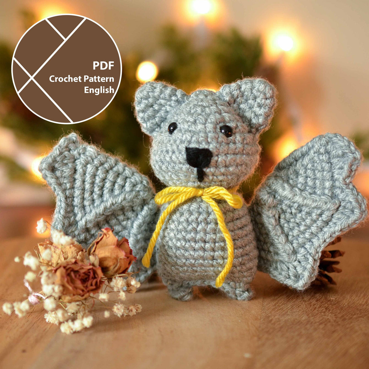 A crocheted bat made by following a crochet pattern, displayed against the Halloween-themed background.