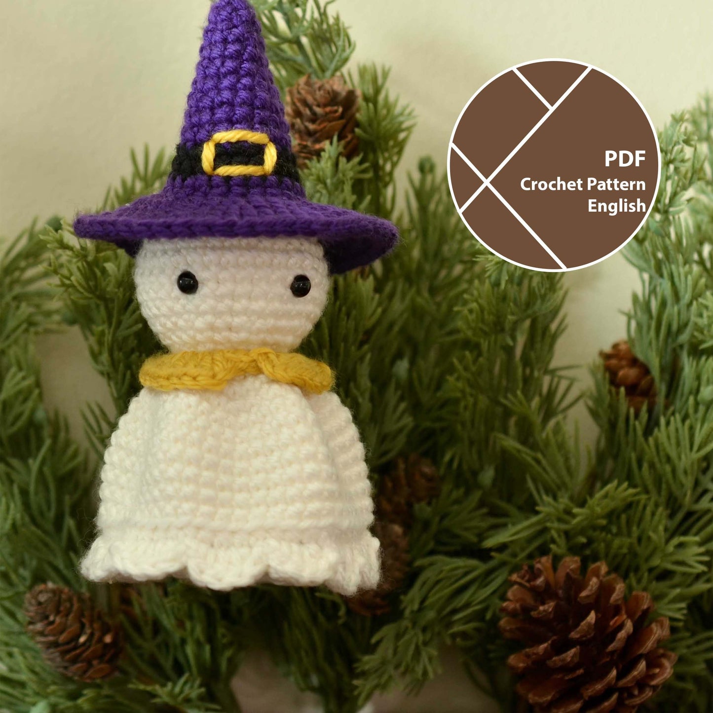 A crocheted ghost wearing a purple witch hat. The ghost has a yellow crocheted collar and black eyes. The ghost is floating in front of a green pine branch.