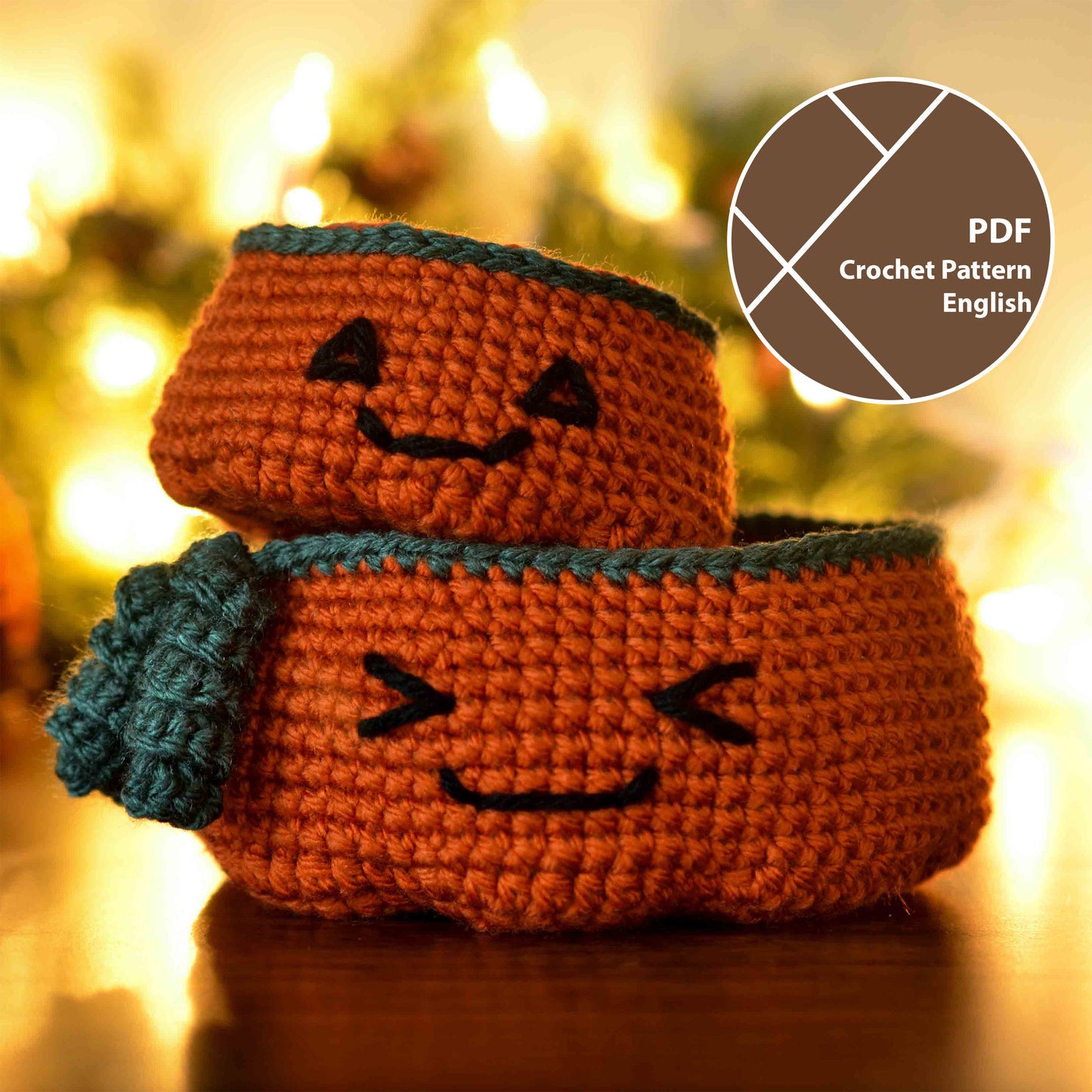 Two crocheted pumpkin-shaped baskets. The larger basket is larger and has a smiling face. The smaller basket has a Halloween-themed face. The smaller one is stacked on the top of the larger one.