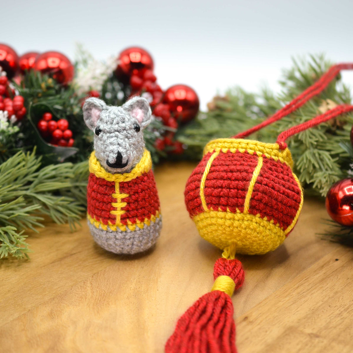 Crocheted mouse ornament and red lantern with festive decorations in the background