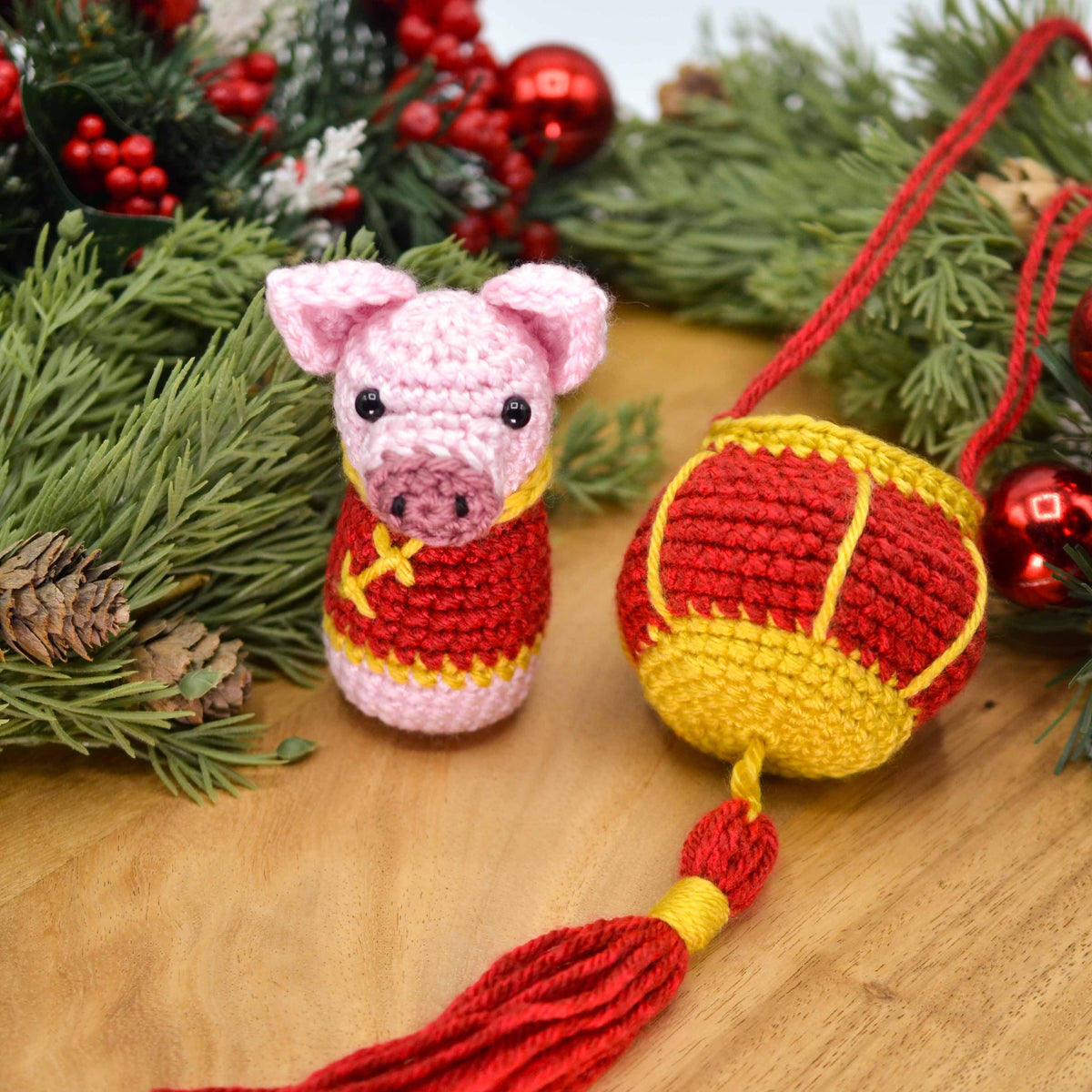 Crocheted pig ornament and red lantern displayed on a wooden surface