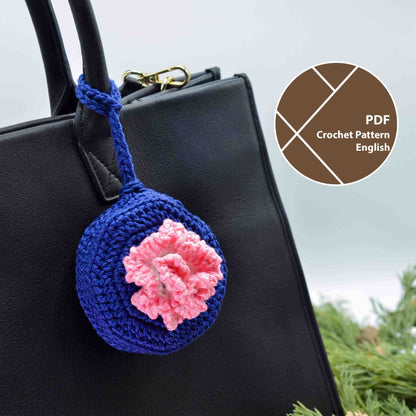 A crochet pattern for a bag charm, featuring January's birth month flower, Carnation. The charm is hanging on a handbag.