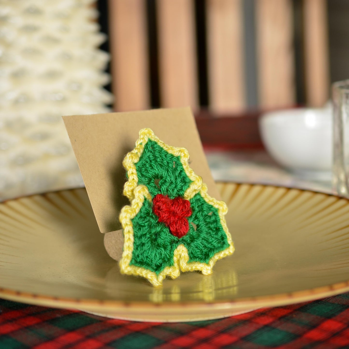 A crocheted holly leaf used for holding a named card on a dinner table.