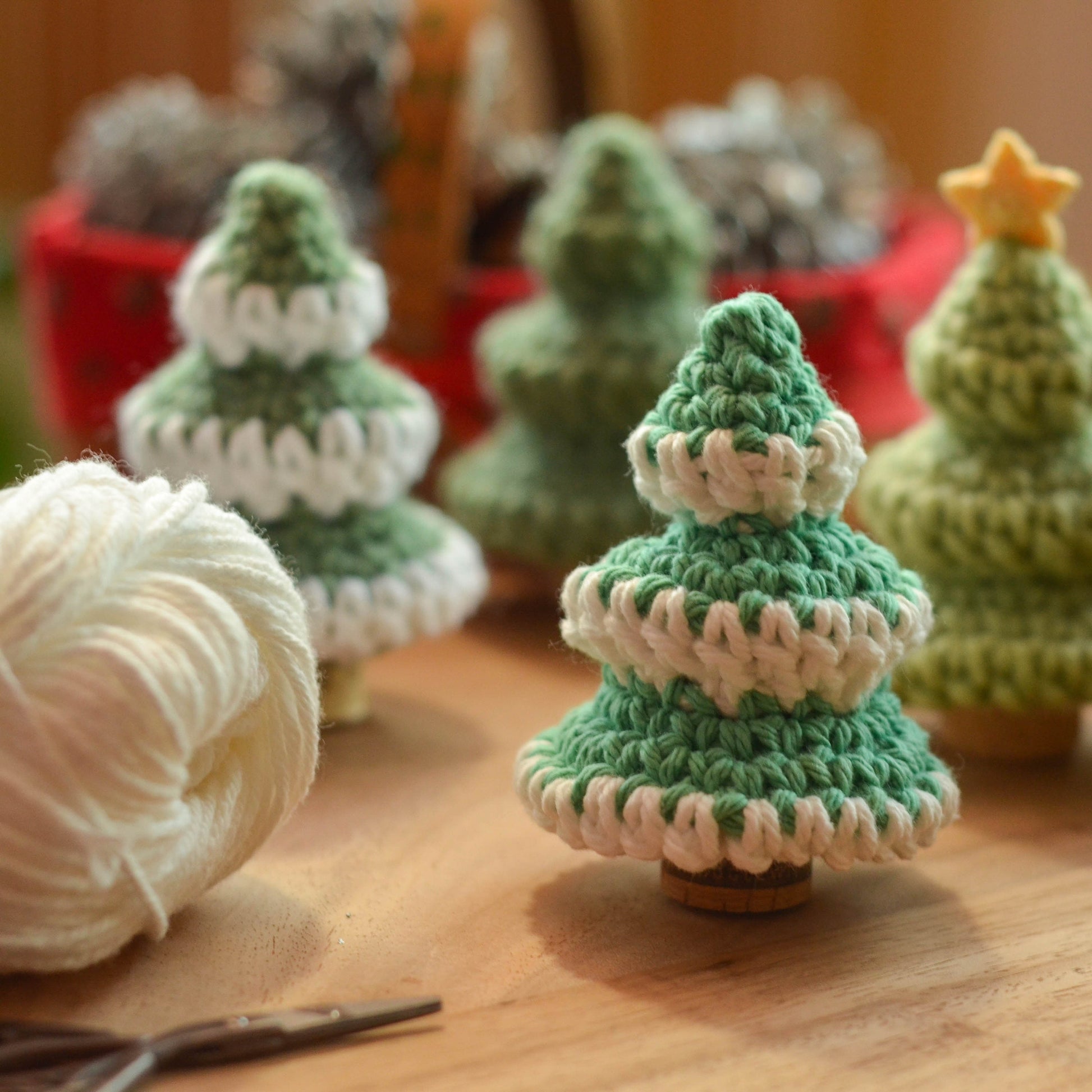 Several crocheted mini Christmas Tree standing on the table. There are snow-like patterns on some of the pine trees. 