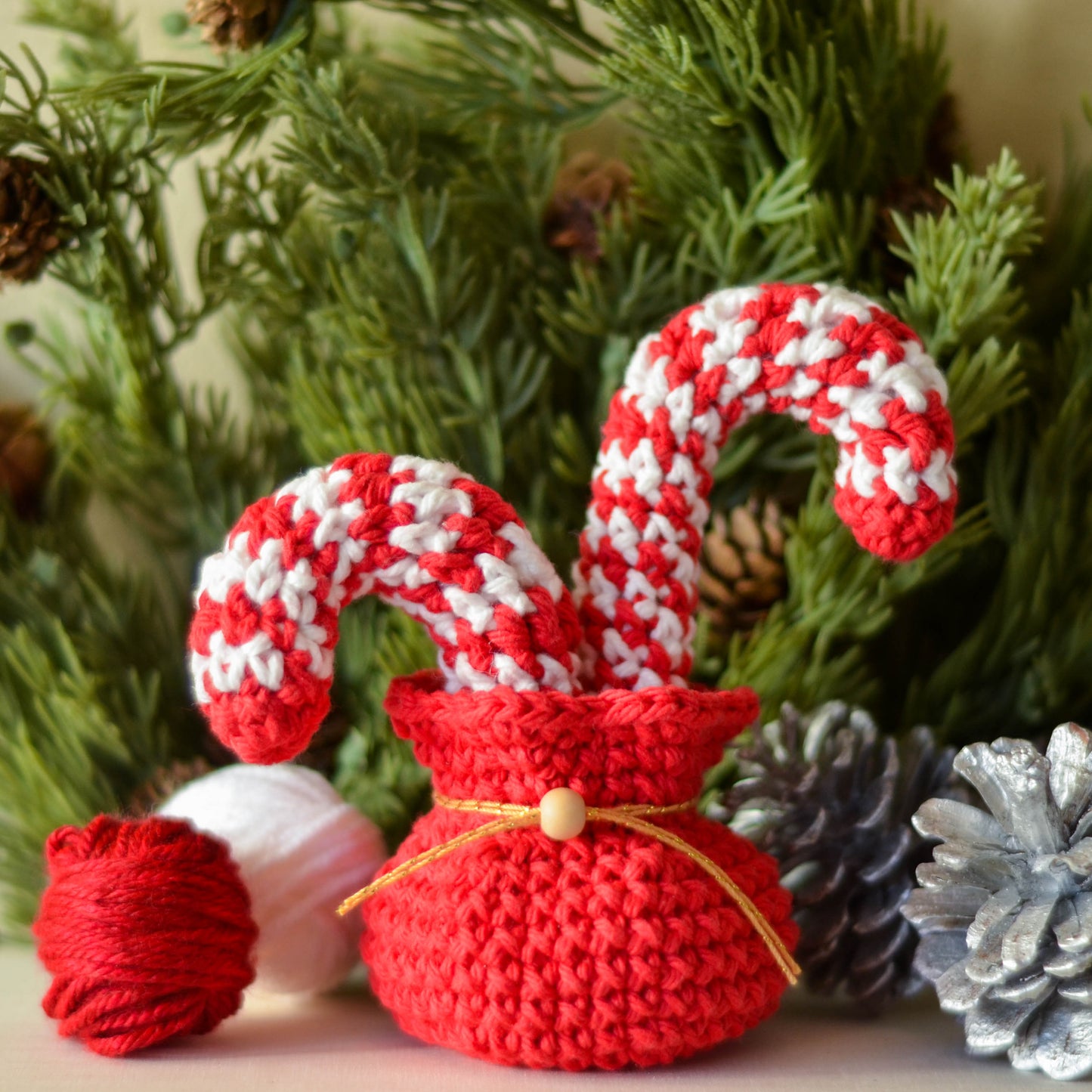 Two red and white striped candy canes are placed in a red crocheted bag. The bag is sitting on a white surface.