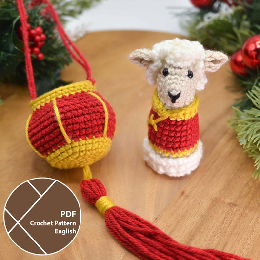A crocheted sheep wearing Lunar-New-Year style clothing. A crocheted red lantern is next to the sheep. A label indicates that this listing is a PDF crochet pattern, written in English.