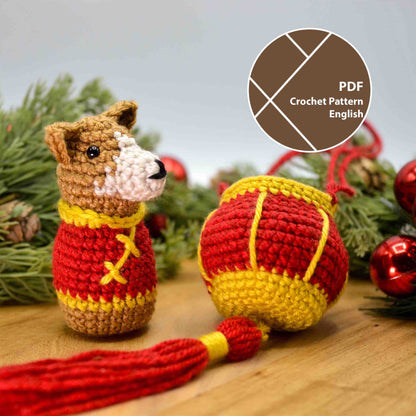 A crocheted dog wearing Lunar-New-Year clothing sitting on a wooden surface. A crocheted red lantern is next to the dog. A label on the upper right corner indicates that this is listing is a crochet pattern PDF, written in English.
