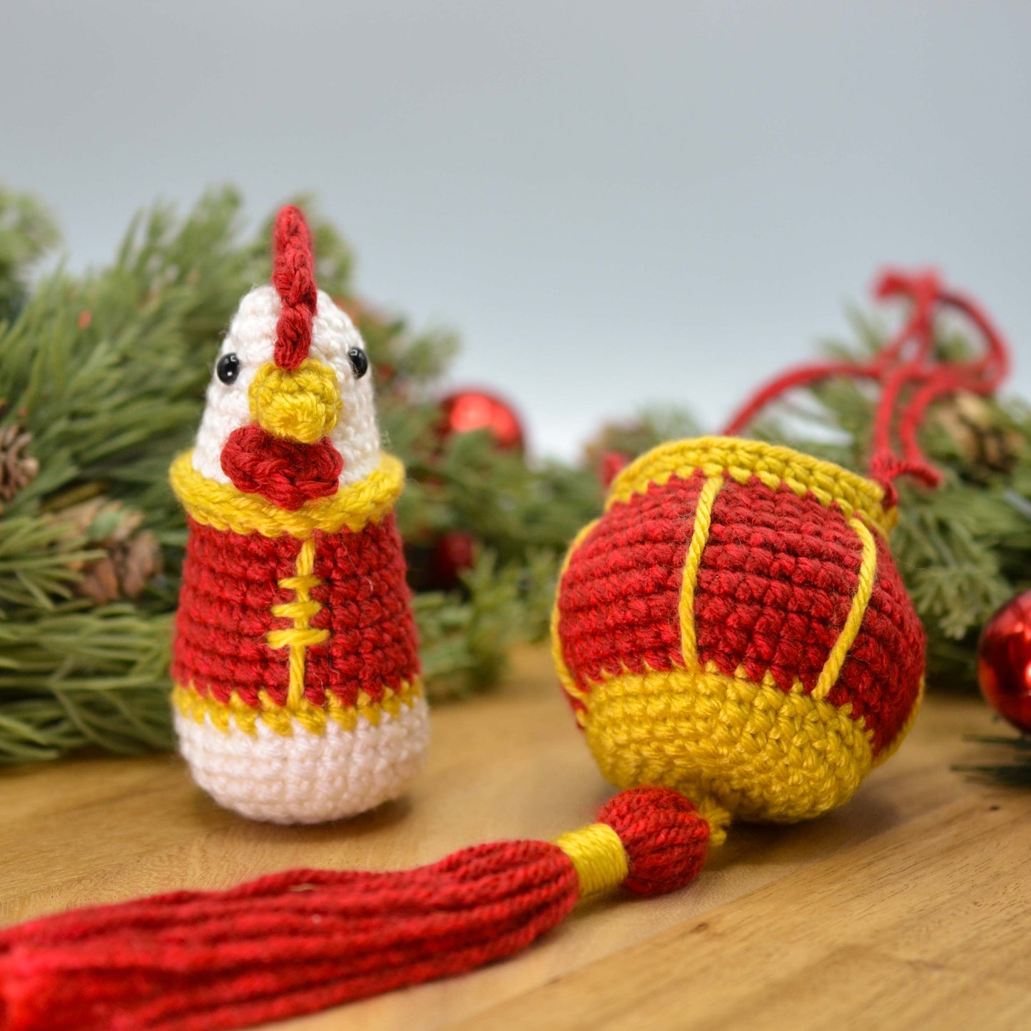 crocheted rooster and red lantern on a wooden surface. The rooster is facing front.