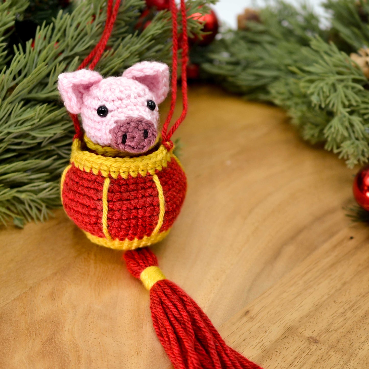 A crocheted pig ornament, for celebrating Lunar New Year, is placed on a wooden surface. 