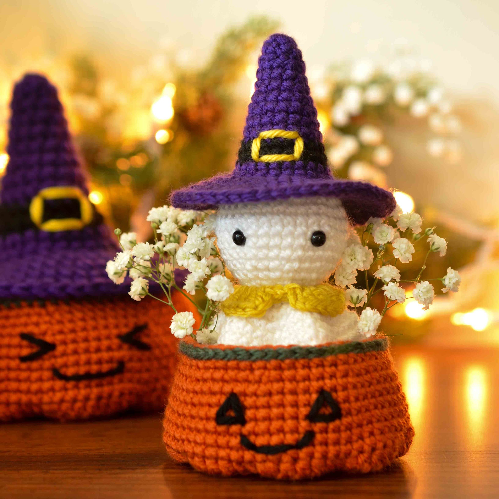 The result of a crochet pattern bundle for making a cute ghost and a pumpkin bowl: A Halloween ghost, wearing a witch's hat, sitting in a pumpkin bowl. In the background, there is a larger pumpkin bowl with a larger-size witch's hat as the cover.