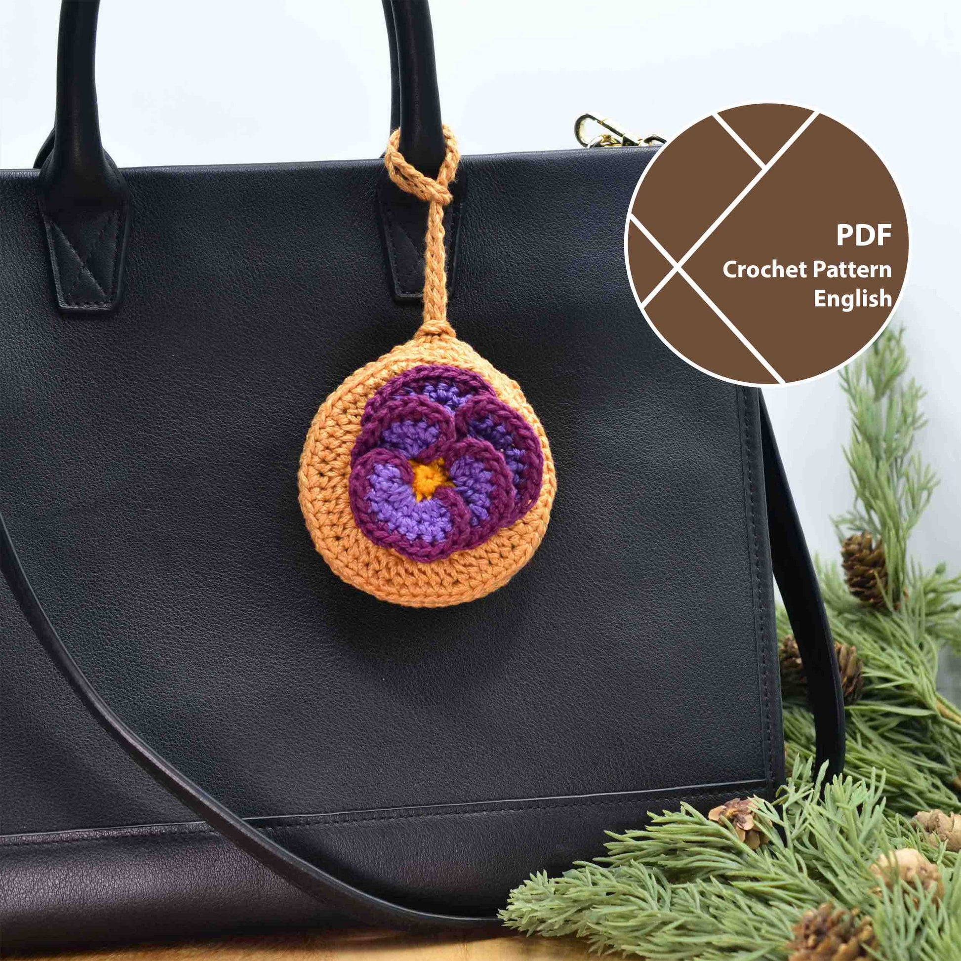 A crocheted pouch with a violet flower on the top. The pouch also doubles as a bag charm, hanging on a white black leather bag. 